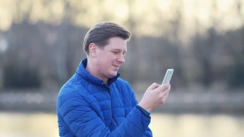 A young attractive man is using a mobile phone at sunset. Video stock 88169254