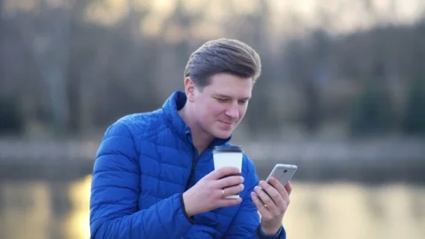 A young attractive man is using a mobile phone at sunset. Stock Footage 88169398