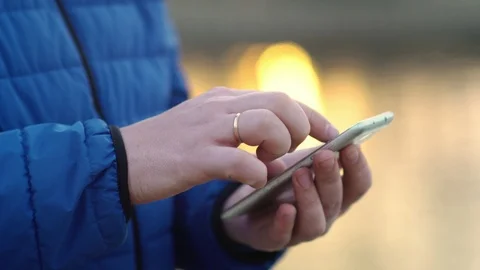 A young attractive man is using a mobile phone at sunset. Video stock 88169714