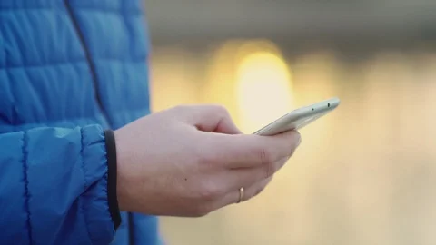 A young attractive man is using a mobile phone at sunset. Video stock 88169964