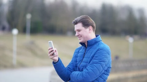 A young attractive man is using a mobile phone at sunset. Video stock 88170184