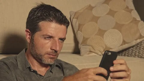 Young attractive man using mobile phone sitting at living room floor Stock Footage 132676047