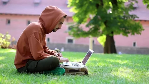 Young attractive man using modern laptop outdoor in sunny green park searching 스톡 동영상 139616525