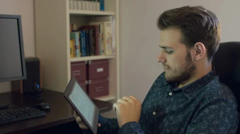 Young attractive man using tablet computer: searching on internet, browsing, web Stock Footage