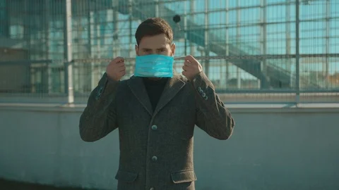 Young attractive man wearing Protective Face Mask sneeze coughs hold suitcase Stock Footage 126581743