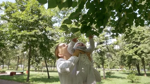 Young attractive momin a good mood is playing with a sweet little child outdoors Stock Footage 138506953