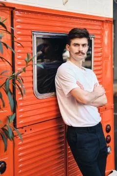 Young attractive mustache man in withe T-shirt leaning on red van holding hands Stock Photos