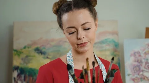 Young attractive painter showing all paintbrushes that she uses in day-to-day Stock Footage 74196666