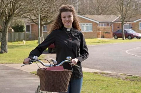 Young attractive parish priest using a bicycle as transport Stock Photos