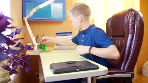 Young attractive schoolboy boy teaches lessons online with tablet at the table.  Stock Footage 138410926