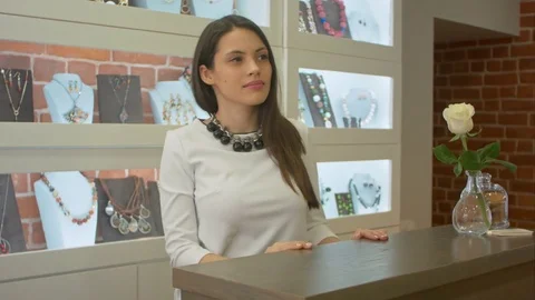Young attractive shopassistant looking on the showcase in jewelry shop Stock Footage