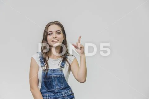 Young attractive student girl shows her index finger up. Tries to concentrate Stock Photos