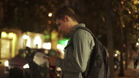 Young attractive student man using his smartphone at the evening street blurred Stock Footage 134383768