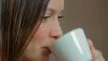 Young attractive woman drinks coffee smiles, pretty face make-up HD Footage