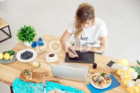 Young attractive woman freelancer sitting front laptop computer drawing on Stock Photos