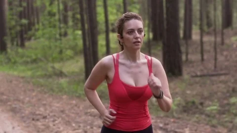 Young attractive woman Jogging in a summer forest. girl with wireless headphones Stock Footage