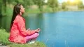 Young attractive woman meditating near the lake at dawn HD Footage