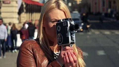 A young attractive woman shoots a video with a camera - closeup - a busy street Stock Footage