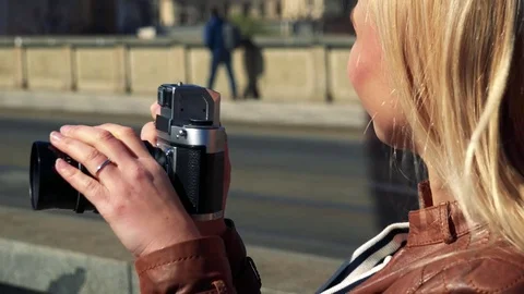 A young attractive woman takes photos with a camera in a street in an urban area Stock Footage