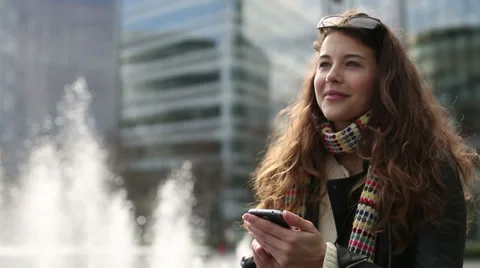 Young attractive woman using her smart phone and smiling outdoors Stock Footage