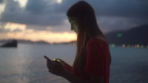 Young attractive woman using her smartphone in the evening on beach 4K Stock Footage 122431338