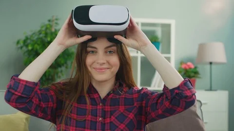 Young attractive woman using virtual reality headset for entertainment siting on Stock Footage 75554979