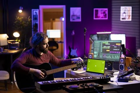 Young audio engineer tuning his acoustic instrument strings by twisting knobs 스톡 사진