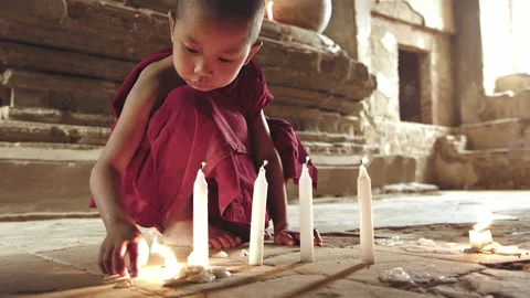 Young authentic real monk boy playing with fire candle in meditation ancient tem Stock Footage 201097014