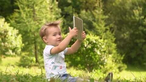 Young Baby Boy Using Tablet Computer Outside At Park. Stock Footage 79413311