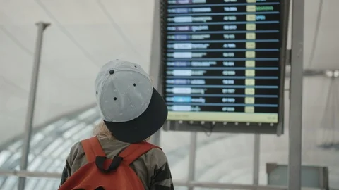 Young backpacker checking flight information on digital schedule display Vidéo 104606138