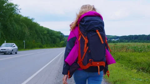 Young backpacker walking on roadside, seeking transportation Video stock 306225775
