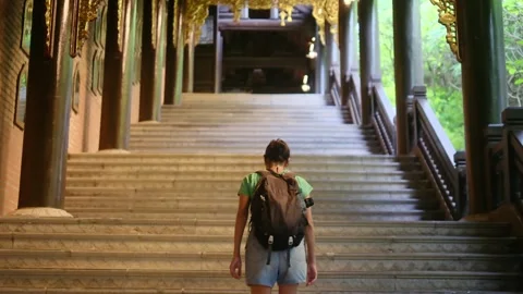 A young backpacker woman with camera exploring a temple in Asia Видео 248513975