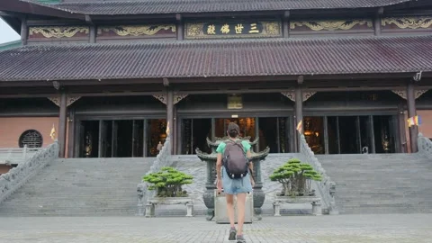 A young backpacker woman with camera exploring a temple in Asia Stock Footage 248514016