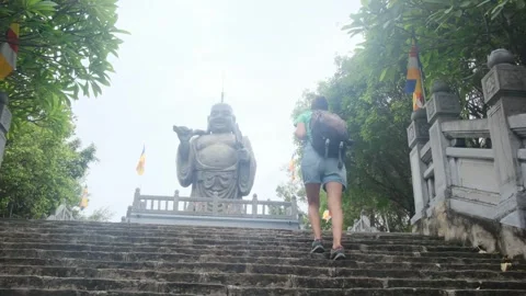 A young backpacker woman with camera exploring a temple in Asia Stock Footage 248514080