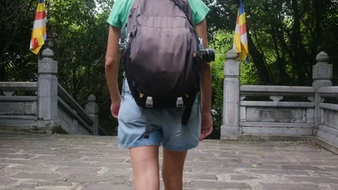 A young backpacker woman with camera exploring a temple in Asia Stock Footage 248515844