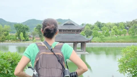 A young backpacker woman with camera exploring a temple in Asia Stock Footage 248515864