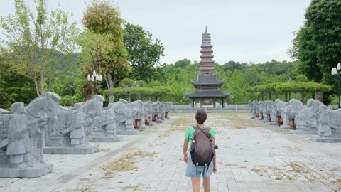 A young backpacker woman with camera exploring a temple in Asia Stock Footage 248516035