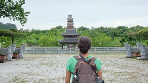 A young backpacker woman with camera exploring a temple in Asia Stock Footage 248516067