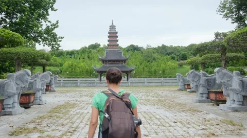 A young backpacker woman with camera exploring a temple in Asia Stock Footage 248516068