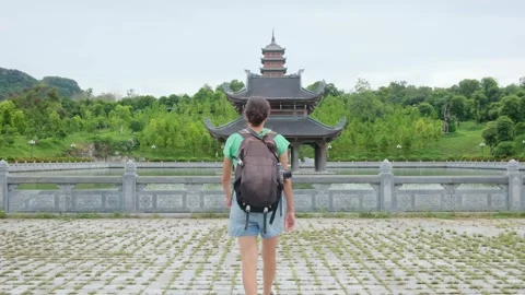 A young backpacker woman with camera exploring a temple in Asia Stock Footage 248516100