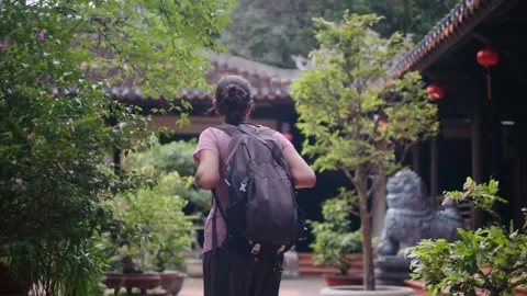 A young backpacker woman with camera exploring a temple in Asia Stock Footage 248525386