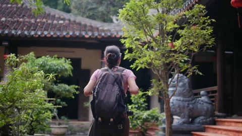 A young backpacker woman with camera exploring a temple in Asia Stock Footage 248525396