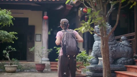 A young backpacker woman with camera exploring a temple in Asia Stock Footage 248525399