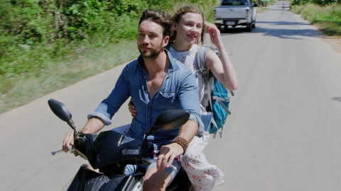 Young backpacking holiday couple having a road trip together on hired Scooter in Stock Footage 201095636