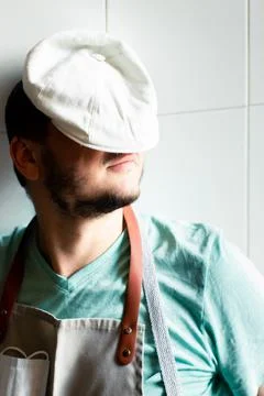 A young baker in a cap and apron sleeps on a work Stock Photos