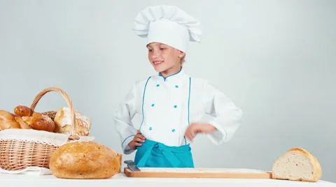 Young baker girl 7-8 years cutting loaf of bread isolated on white Stock Footage