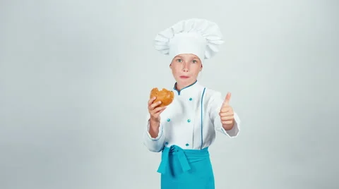 Young baker girl eating small bread looking at camera isolated on white Stock Footage