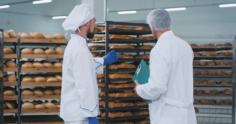 Young baker man and main engineer have a conversation in a bakery section with Stock Footage 112349642