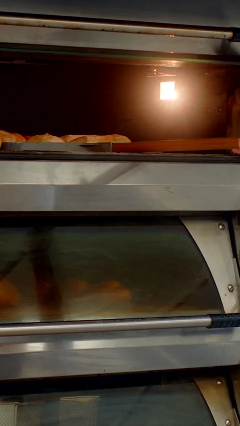 Young baker operating commercial deck oven controls while checking upper chamber Stock Footage 344575695