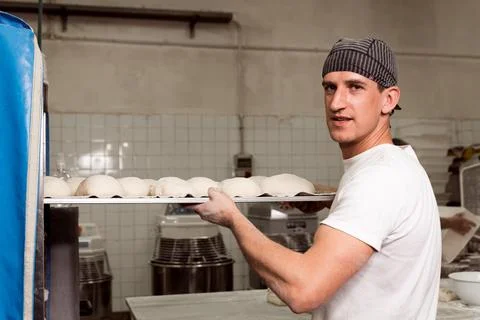 Young baker preparing raw bread knead before cooking with a smile in bread sh 스톡 사진